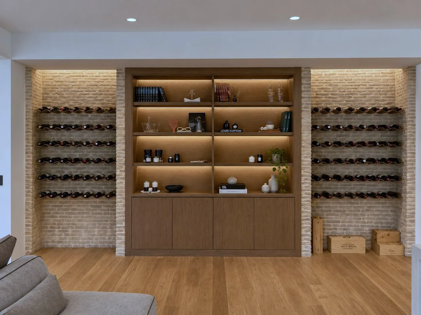 Built-in bookcase flanked by wine racks on brick