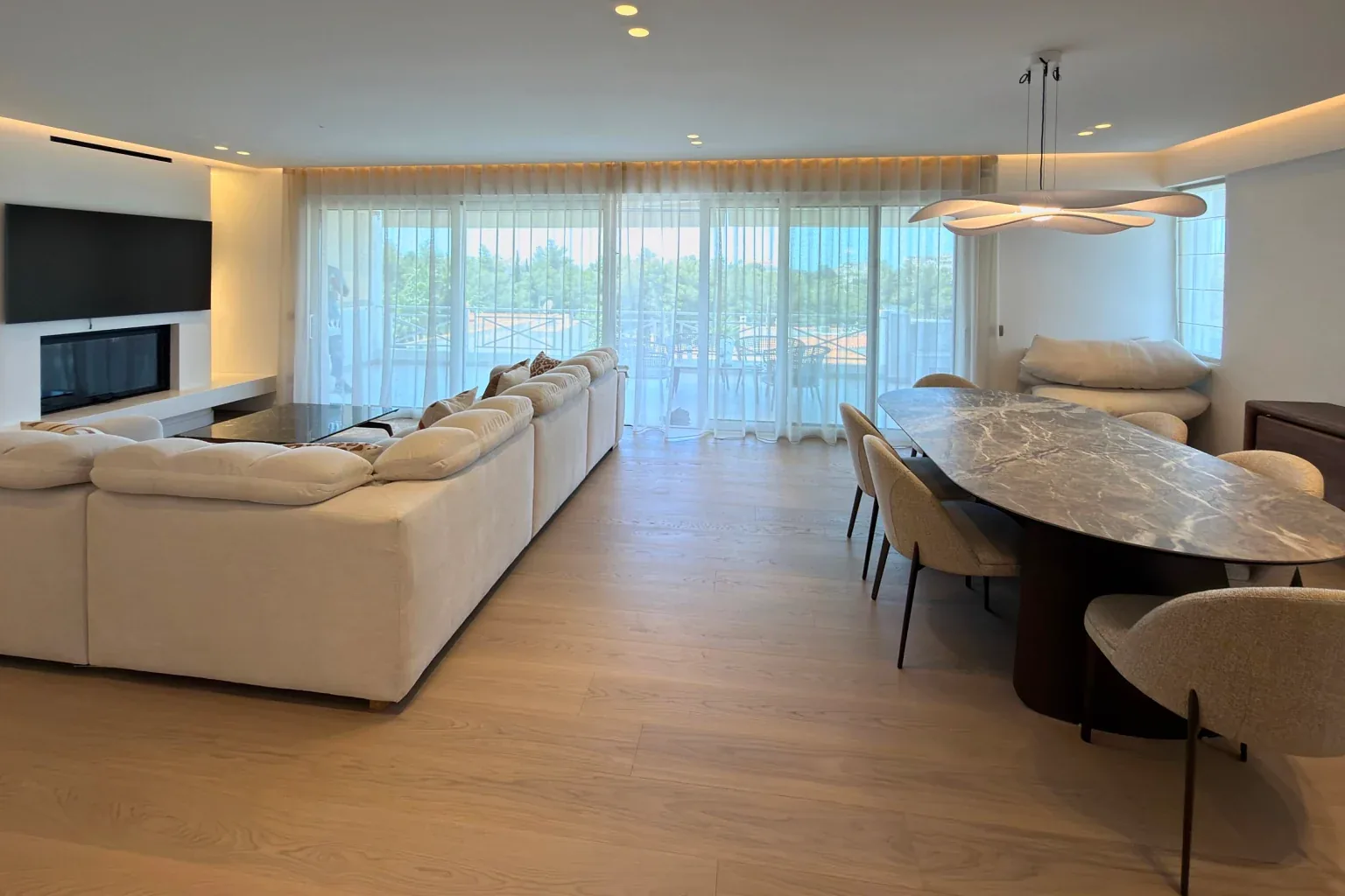 Open living and dining room with sheer curtains and an oak floor